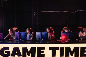 Jogadores participam de um torneio de e-sports em um ambiente interno com iluminação colorida.