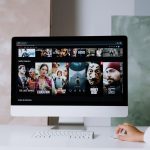 Computador de mesa exibindo uma tela com séries da Netflix em um ambiente de trabalho.