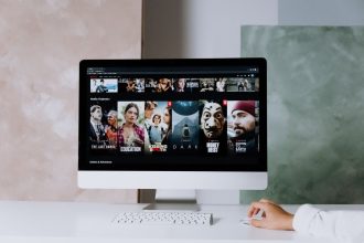 Computador de mesa exibindo uma tela com séries da Netflix em um ambiente de trabalho.