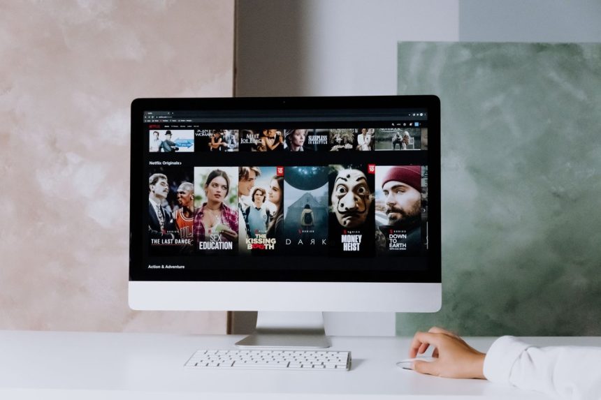 Computador de mesa exibindo uma tela com séries da Netflix em um ambiente de trabalho.