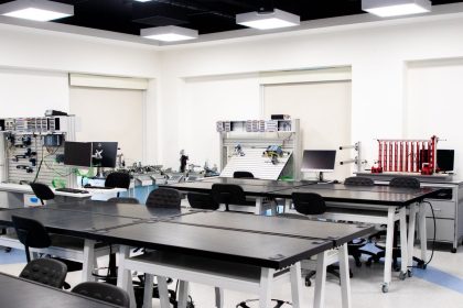 Sala de aula universitária contemporânea com computadores, estações de trabalho e equipamentos tecnológicos.
