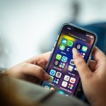 Mulher segura um smartphone que exibe vários aplicativos na tela.