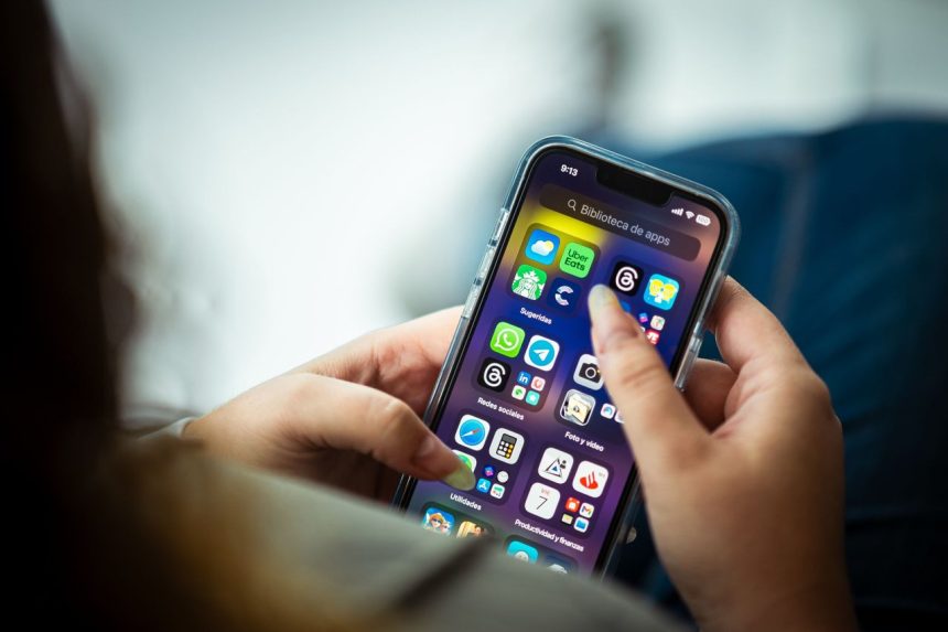 Mulher segura um smartphone que exibe vários aplicativos na tela.