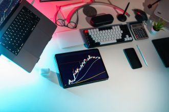 Mesa de escritório com dispositivos digitais exibindo análises financeiras.