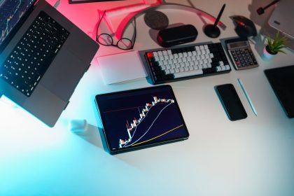 Mesa de escritório com dispositivos digitais exibindo análises financeiras.